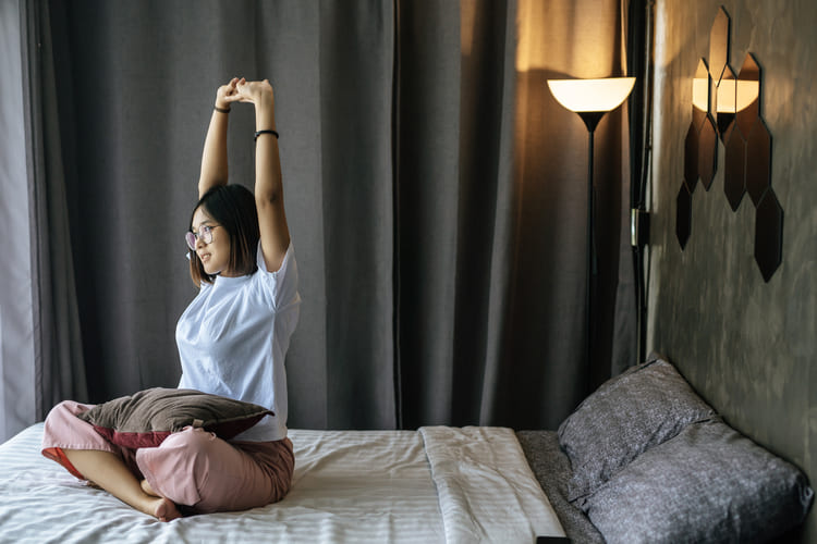 woman-white-shirt-sitting-bed-raising-both-arms (1) (1)