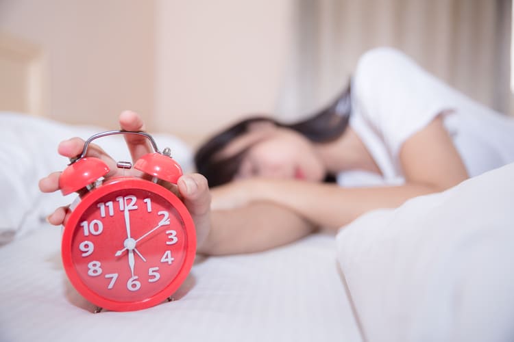 young-sleeping-woman-alarm-clock-bedroom-home